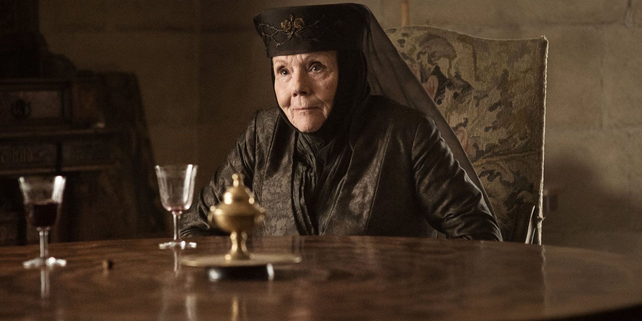 Olenna Tyrell sitting at table with win in Game of Thrones