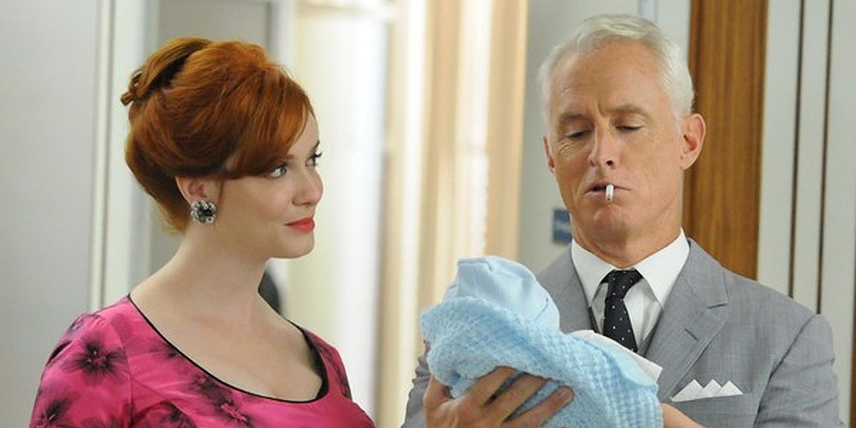 Joan standing next to Roger, who holds baby Kevin in Mad Men