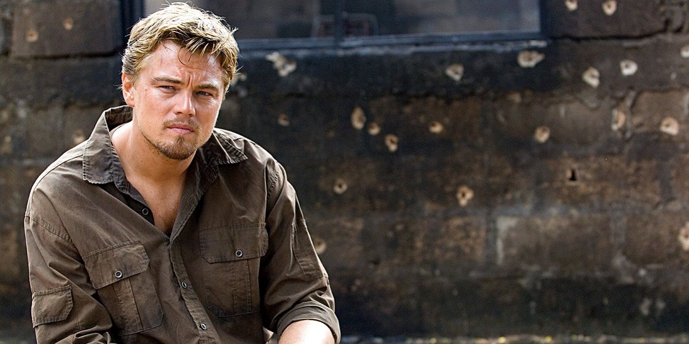 Archer sits in front of a wall full of bullet holes in Blood Diamond