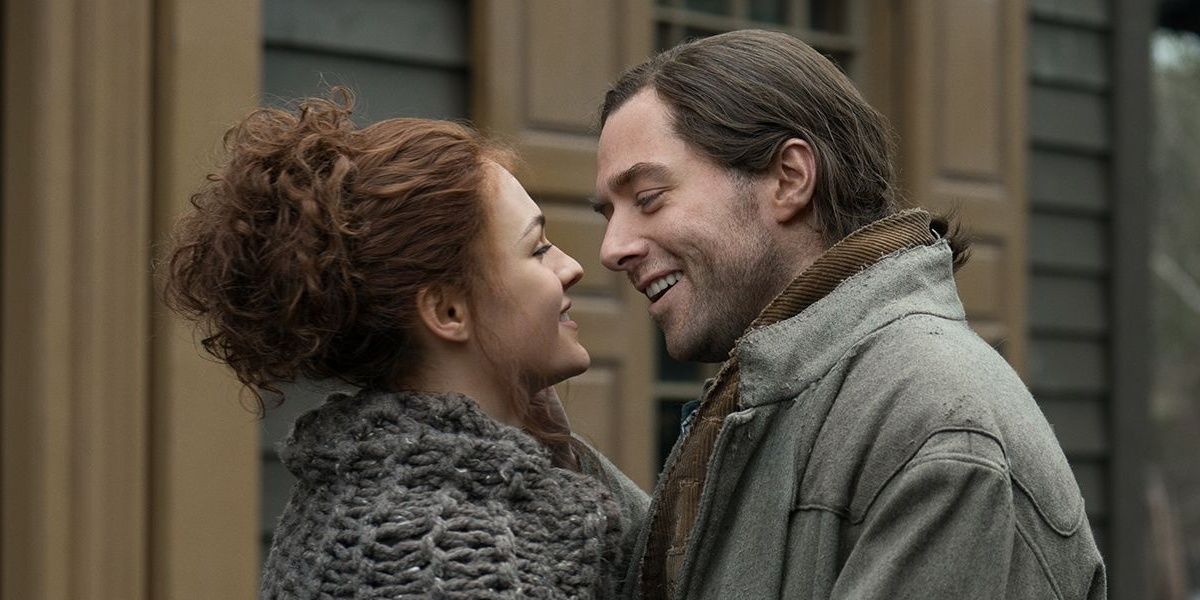Brianna and Roger smile as they're about to kiss in Outlander