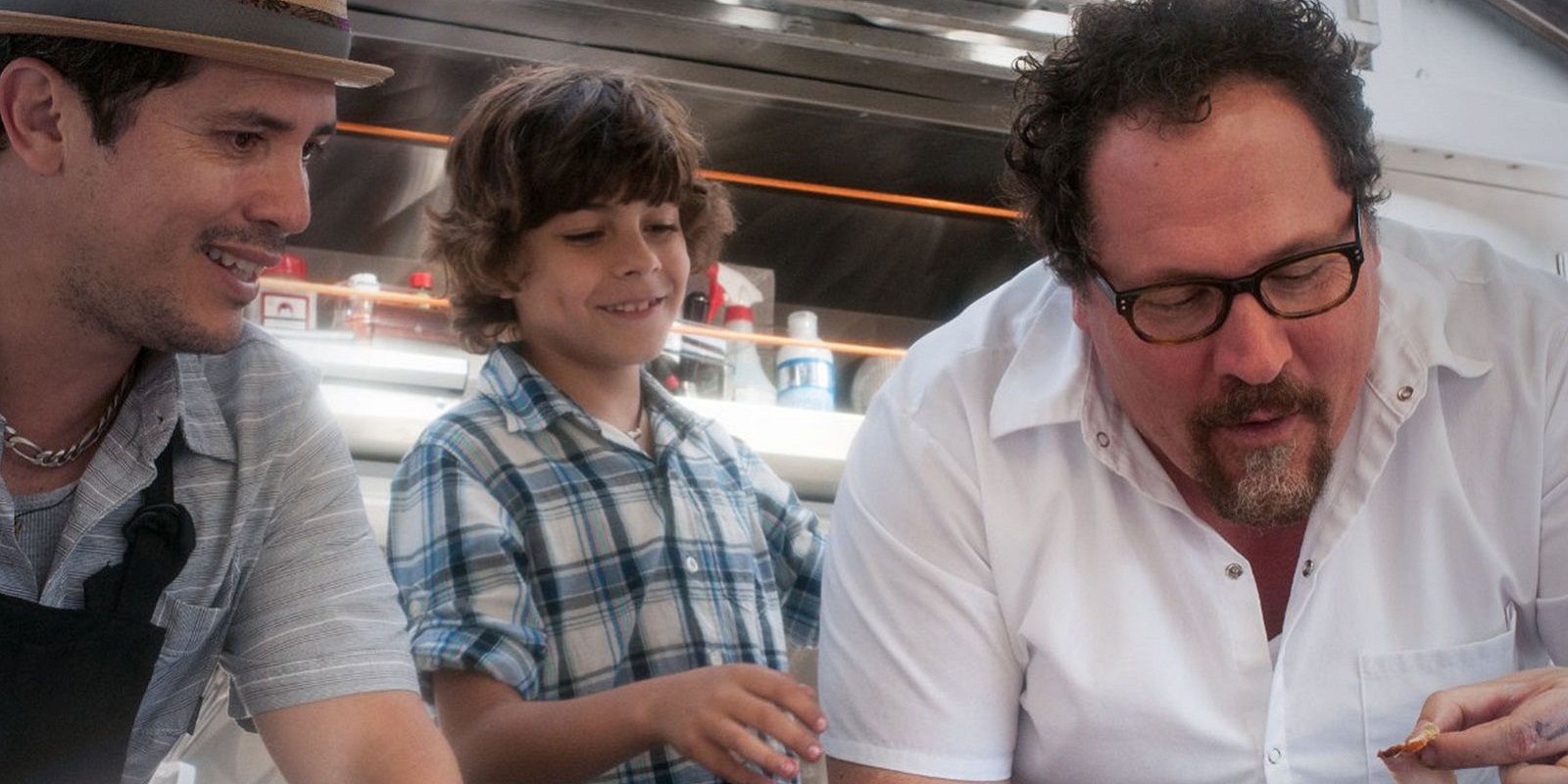 Jon Favreau cooking as his character's son and John Leguizamo look on in Chef