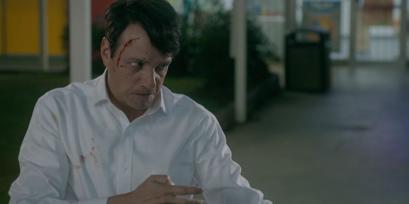 Daniel LaRusso em uma camisa branca, sangue no rosto se preparando para lutar em uma cena de Cobra Kai