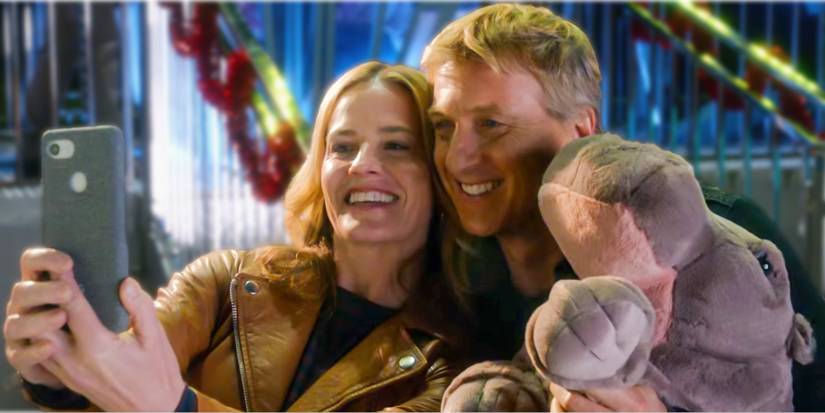 Johnny (William Zabka) and Ali (Elisabeth Shue) smiling at a carnival in Cobra Kai Season 3