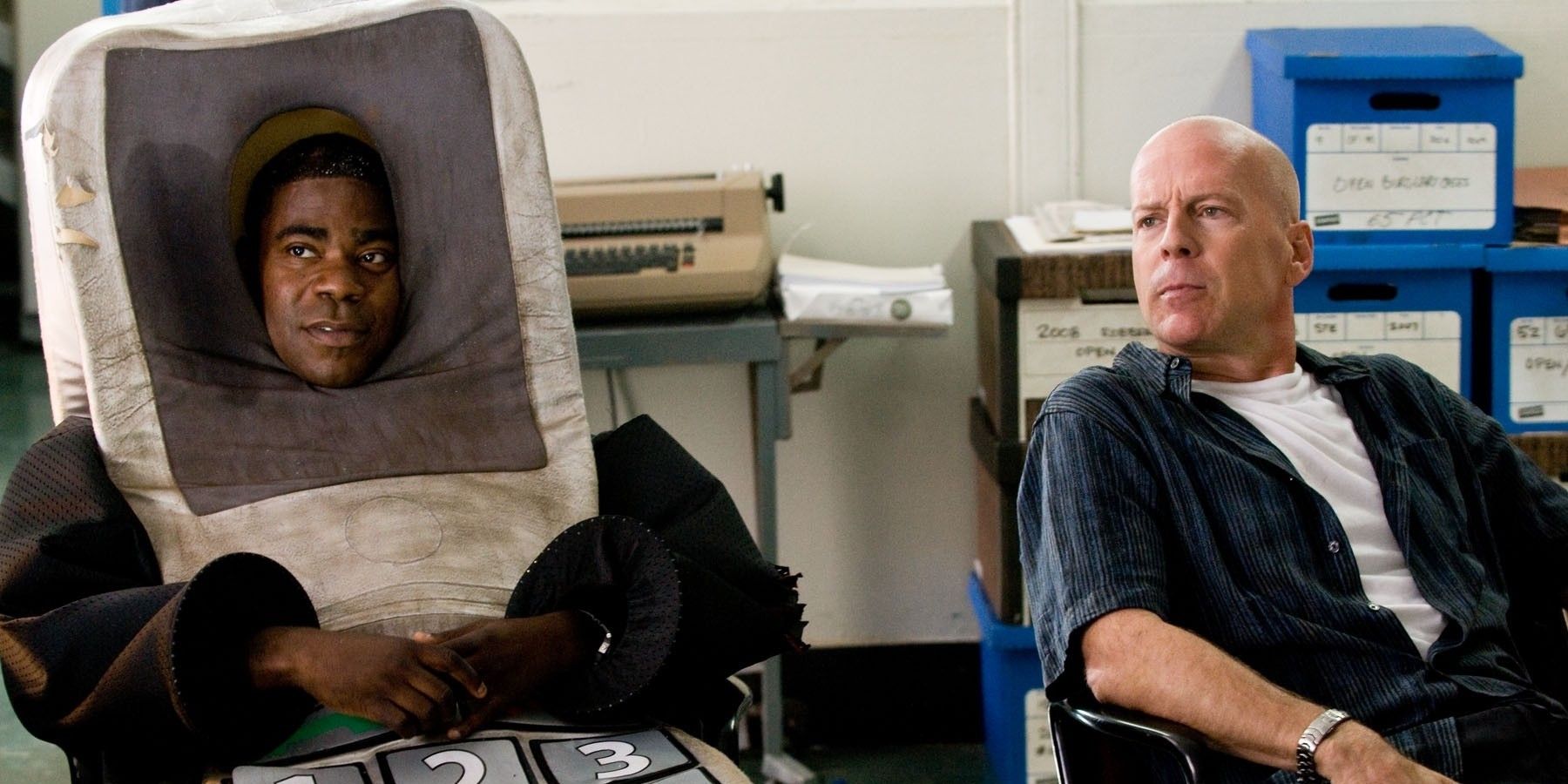 Bruce Willis and Tracy Morgan in costume sit next to each other in Cop Out