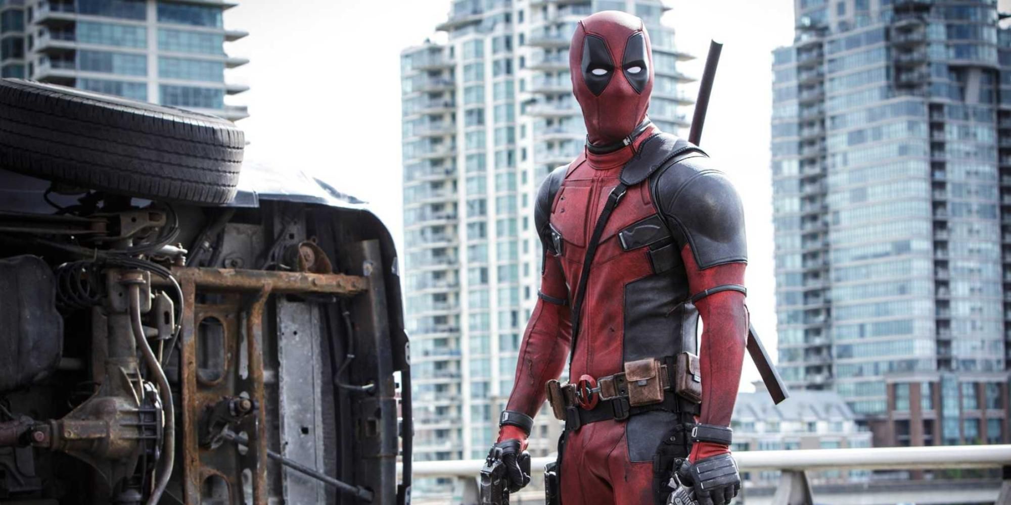 Deadpool stands in front of a overturned car in Deadpool