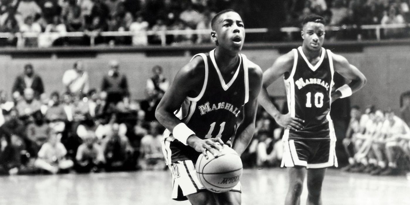 A black and white still from Hoop Dreams showing two young men on a basketball court