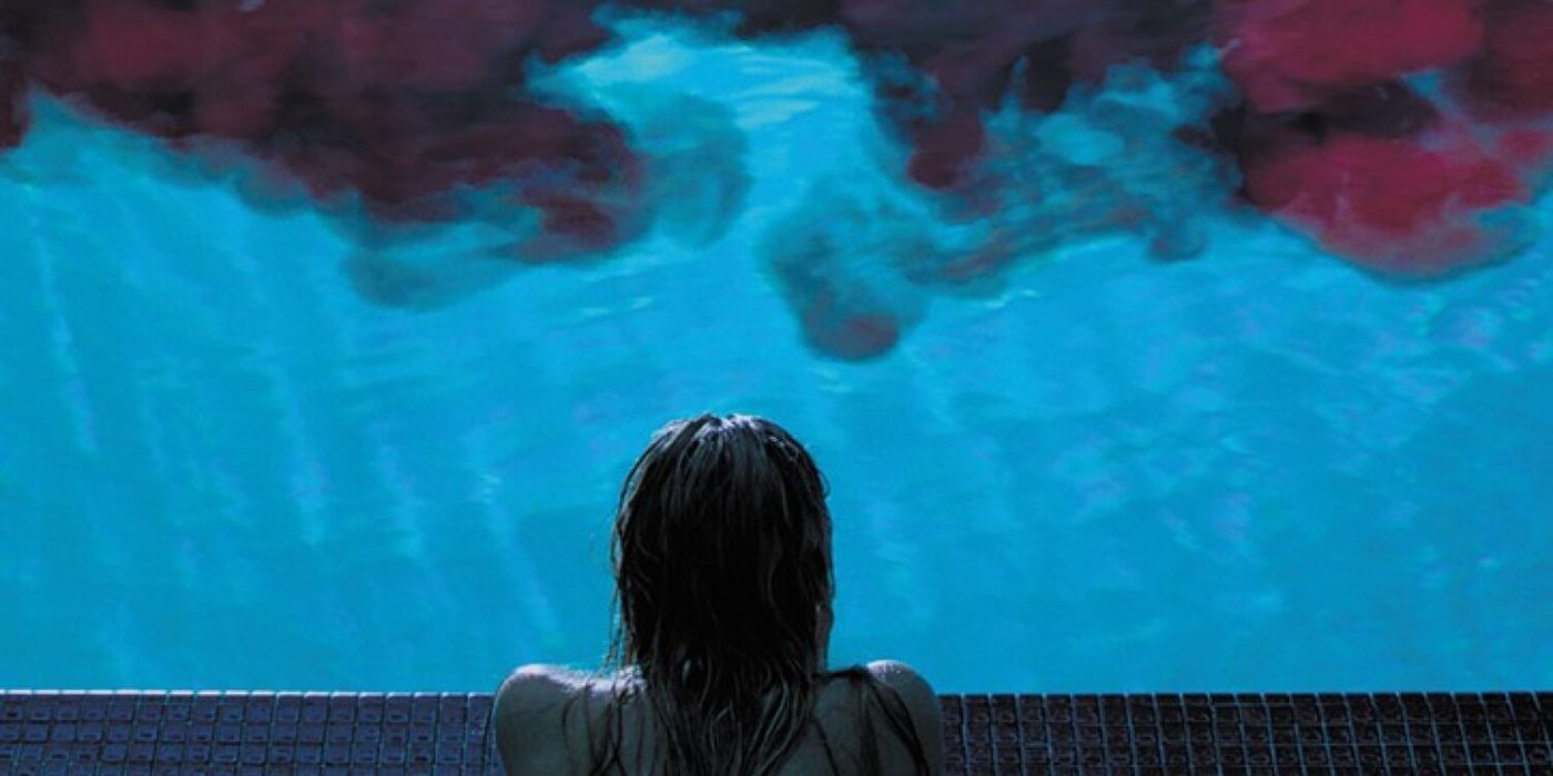 Jay (Maika Monreo) looking at blood flowing their a pool in It Follows