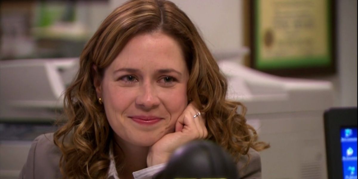Pam smiling while resting with her face in her hand in The Office