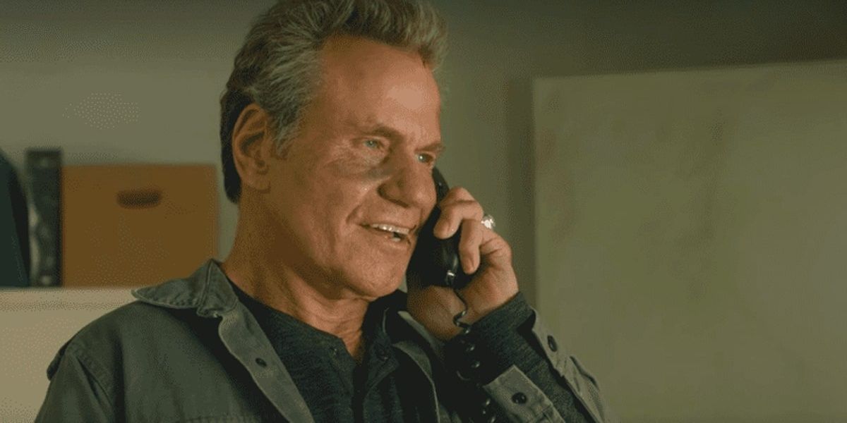 John Kreese sorrindo durante uma ligação em uma cena de Cobra Kai