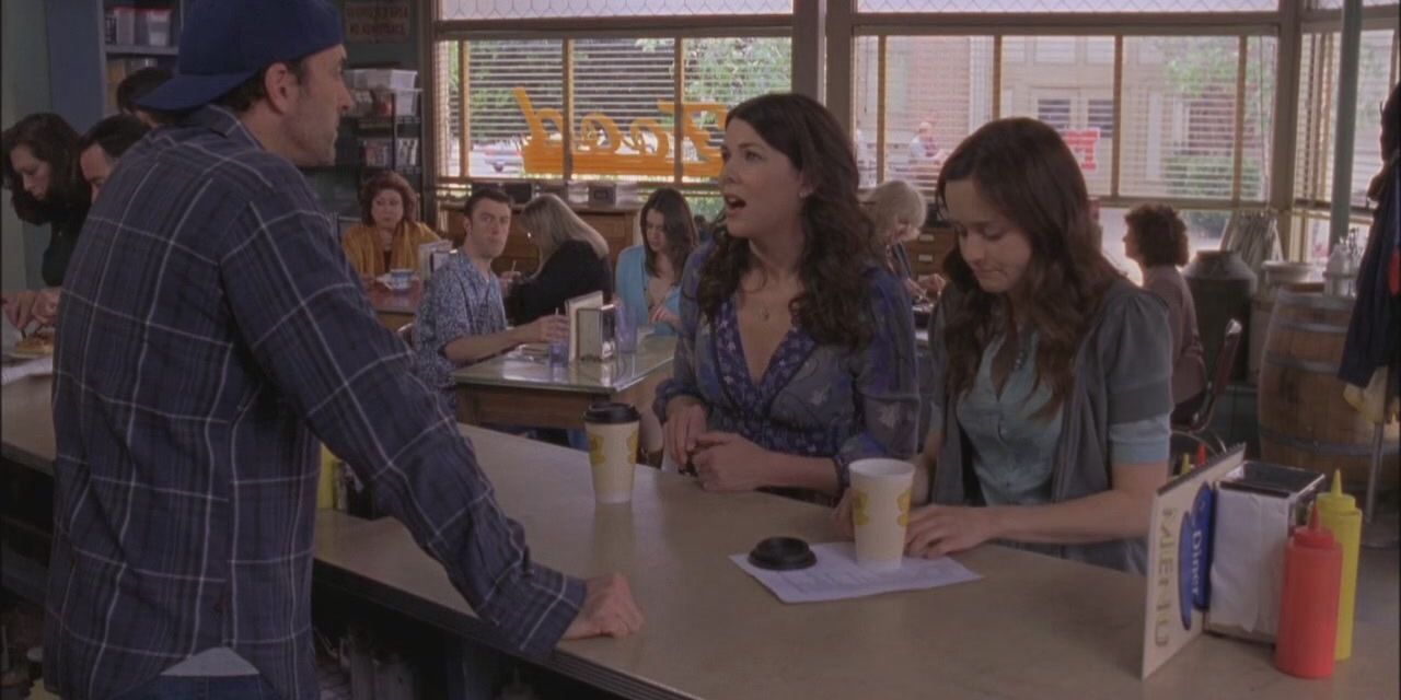 Lorelai and Rory sitting at Luke's Diner counter with coffee, served by a grumpy Luke