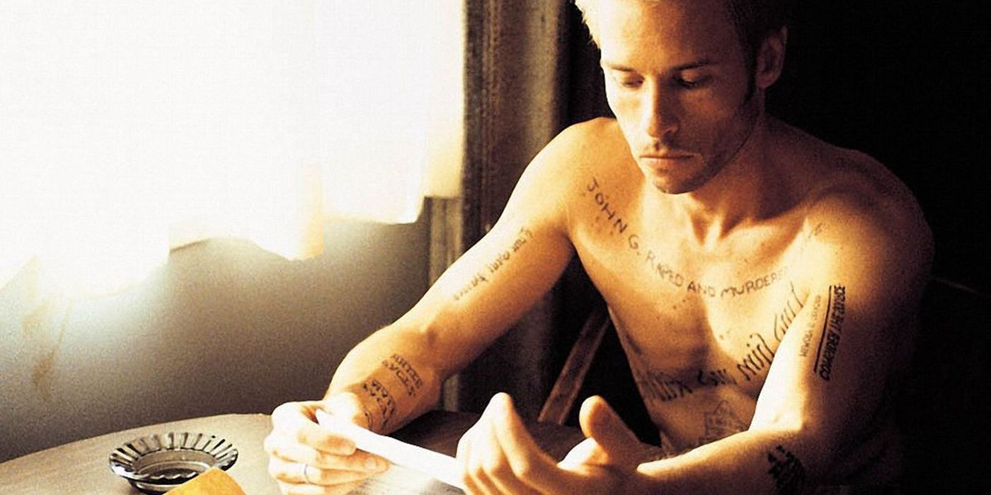 Guy Pearce as Leonard Shelby sits at a table in Memento.