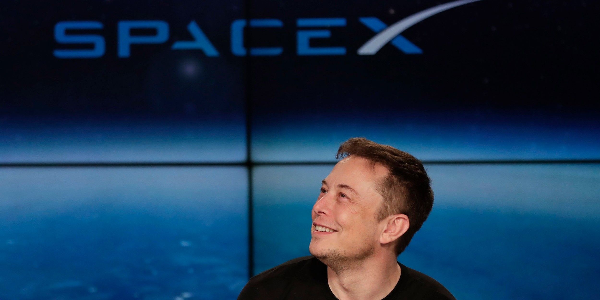 Elon Musk in front of SpaceX sign