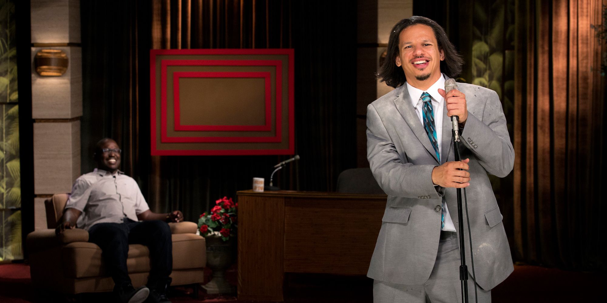 Eric Andre in front of a microphone smiling in The Eric Andre Show
