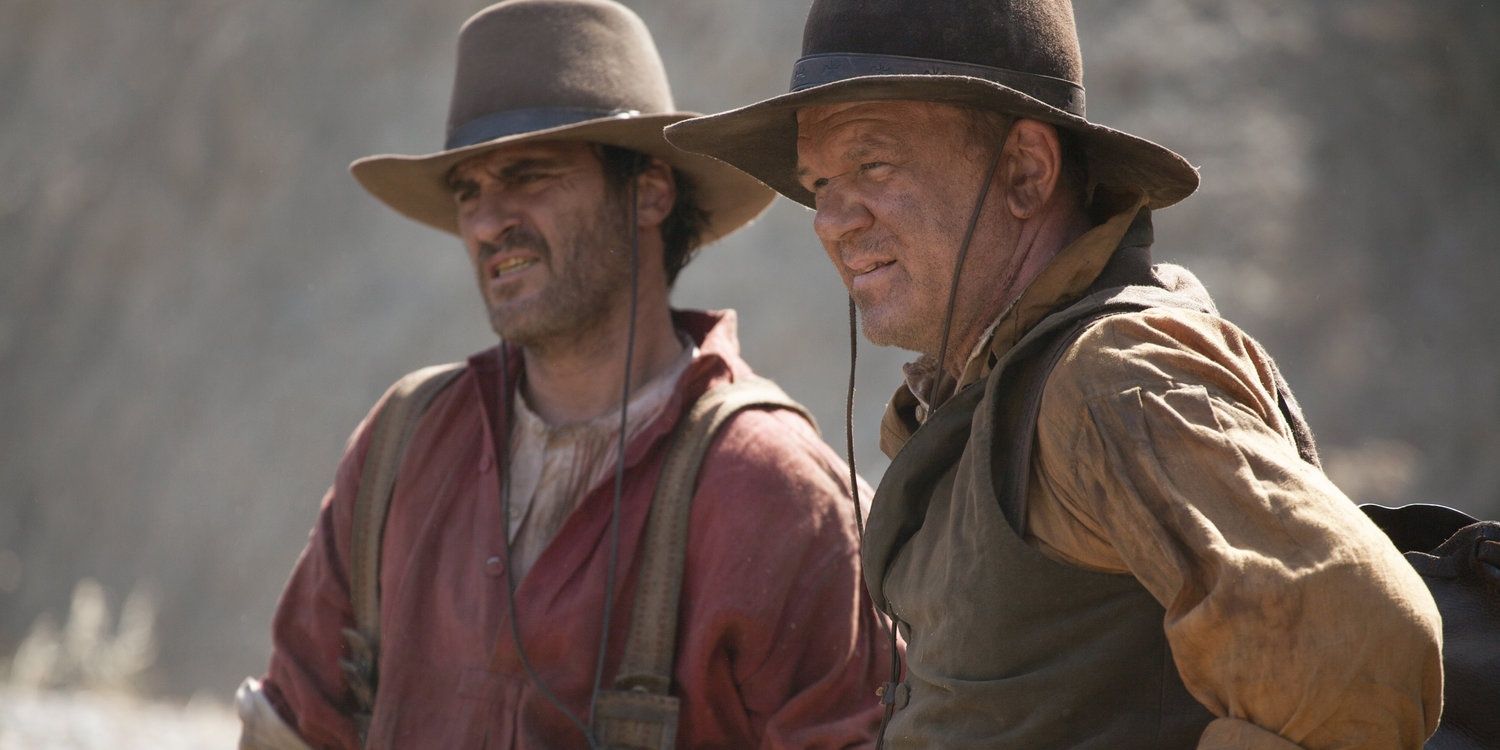Joaquin Phoenix and John C. Reilly looking at something in The Sisters Brothers