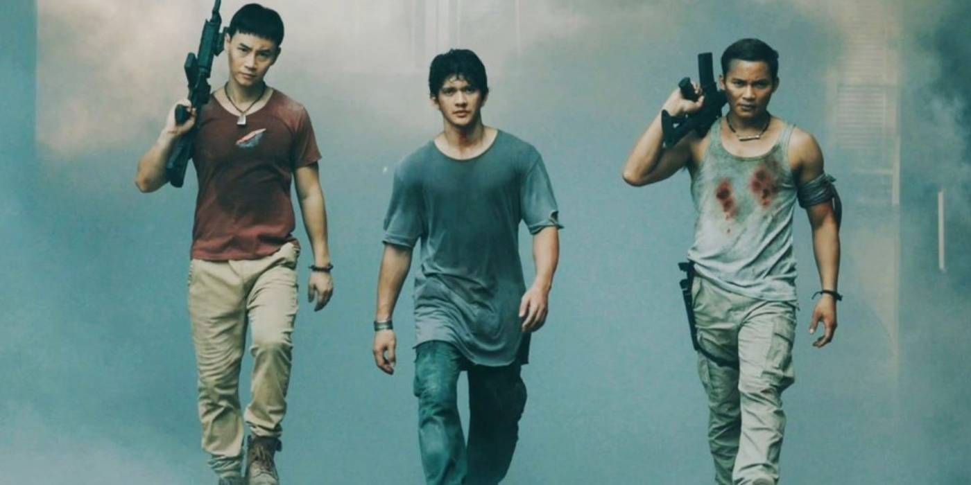 Tiger Chen, Tony Jaa, and Iko Uwais walking in a still from Triple Threat while Jaa and Chen also hold guns in their hands.