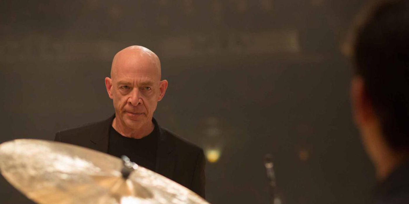 Fletcher (J. K. Simmons) looks over top of a drum set in Whiplash