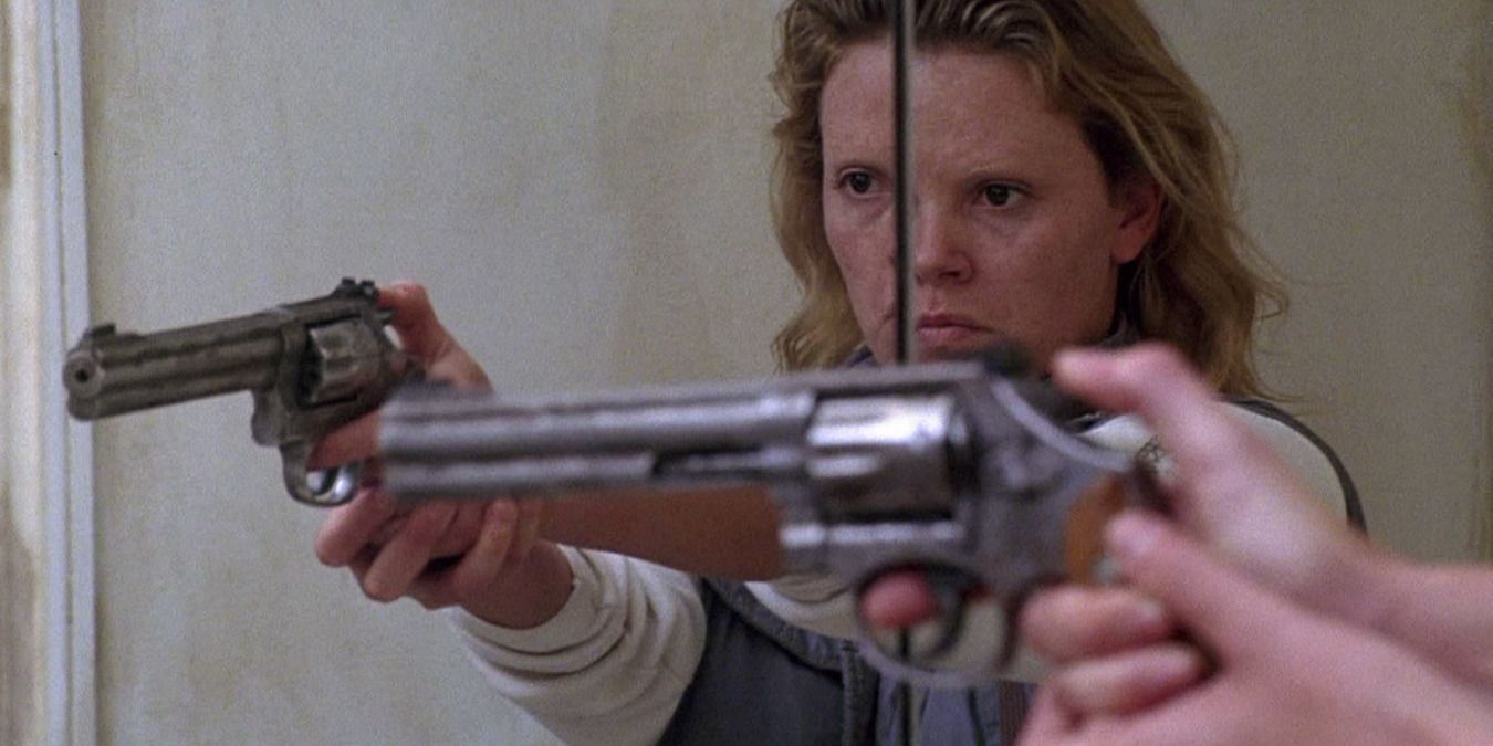 Charlize Theron pointing a gun at the mirror in Monster (2003)