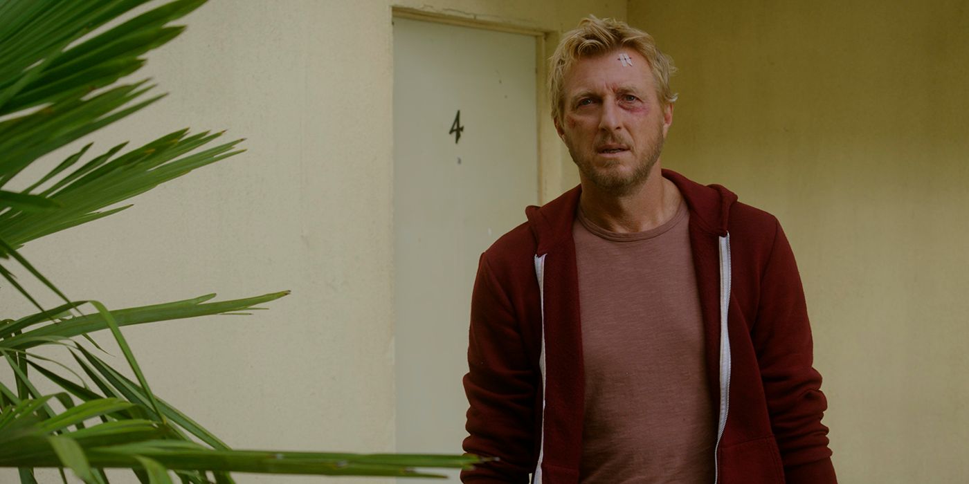 Johnny Lawrence looking beat up, standing by his door in a scene from Cobra Kai