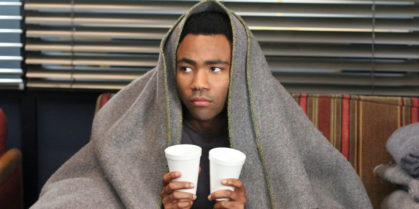 Tory Barnes wrapped in a blanket and holding two cups in Community