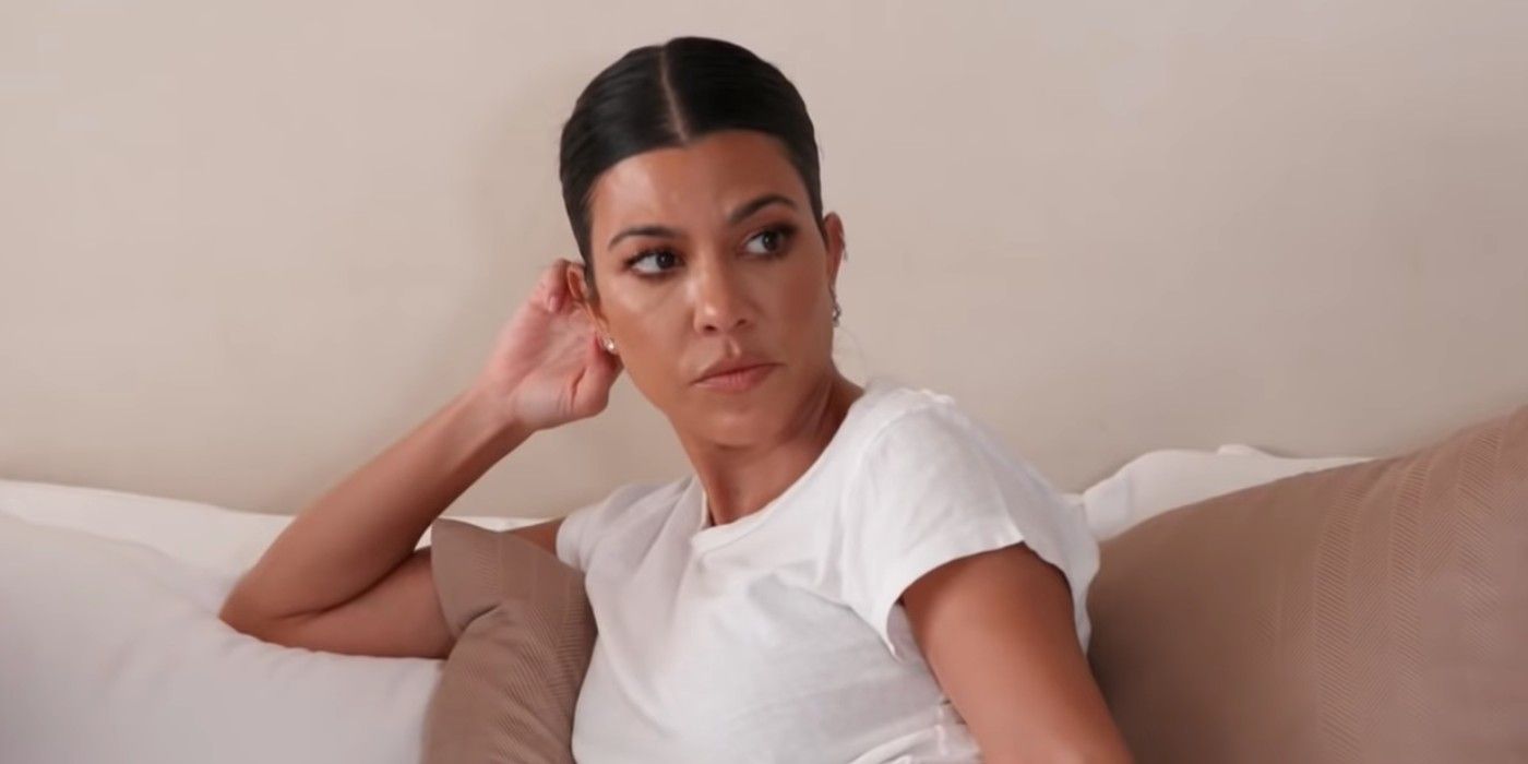 Kourtney Kardashian, estrela das Kardashians, de camiseta branca no sofá