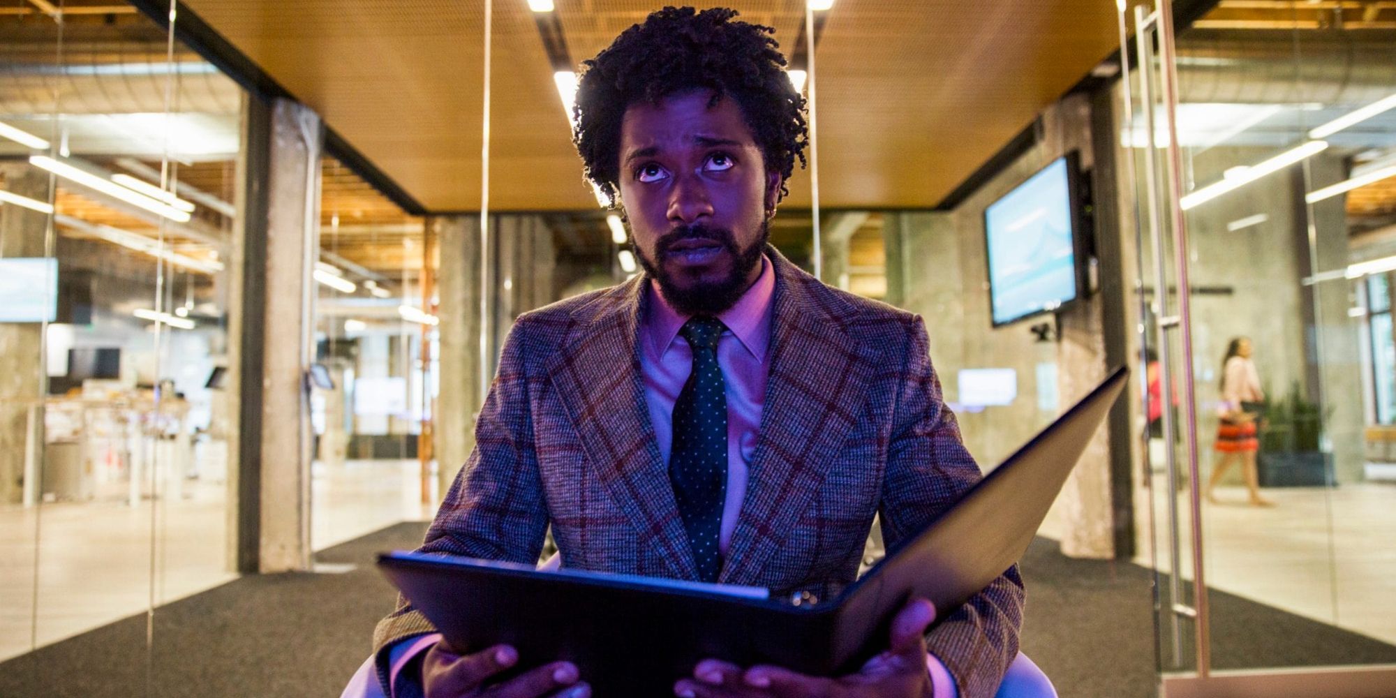 Cash looking up while holding an open book in Sorry To Bother You