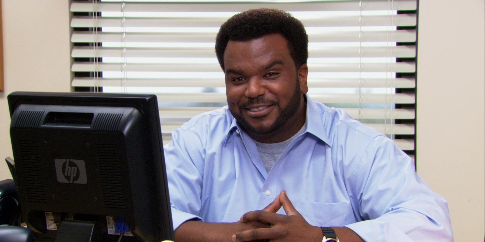 Darryl sitting behind a desk, talking to the camera on The Office