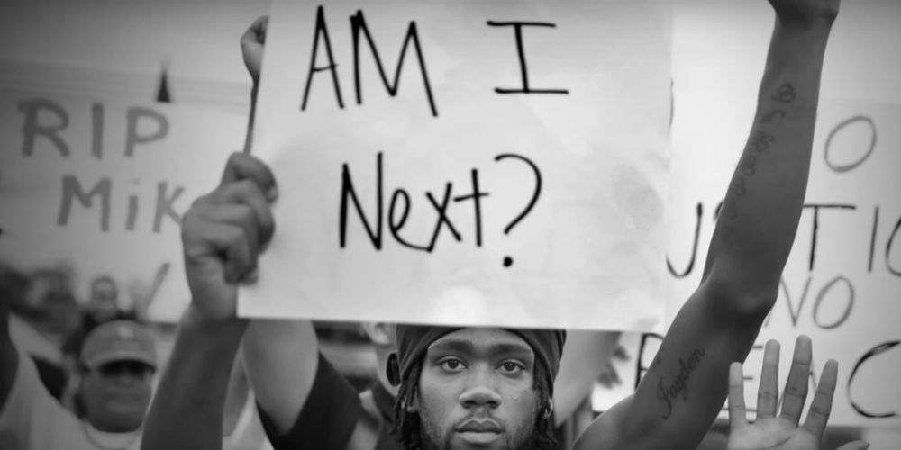 A Black protester holding up a sign that reads &quot;Am I Next?&quot; in the documentary 13th