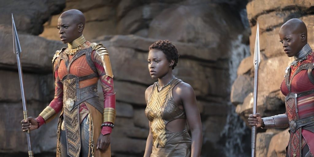 Nakia, Okoye, and Ayo from Black Panther stand near the waterfall.