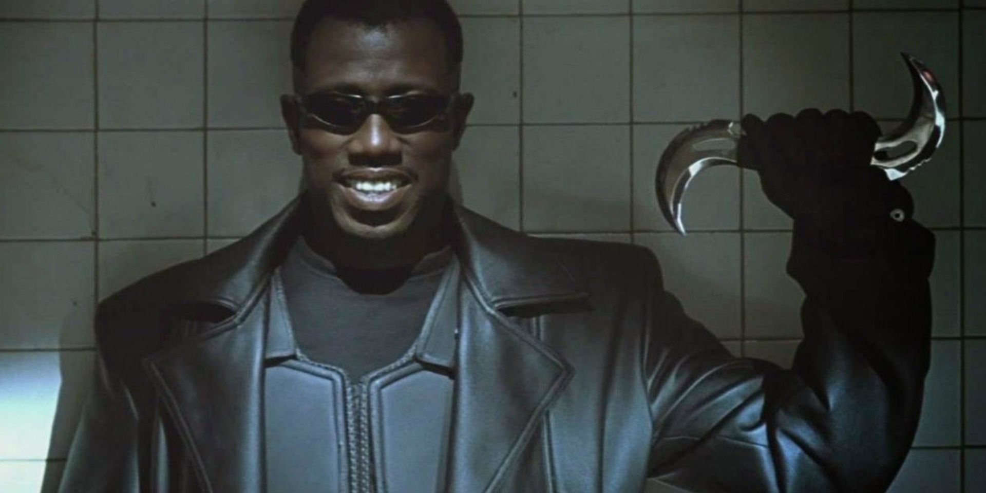 Blade holding up a weapon and smiling in Blade.