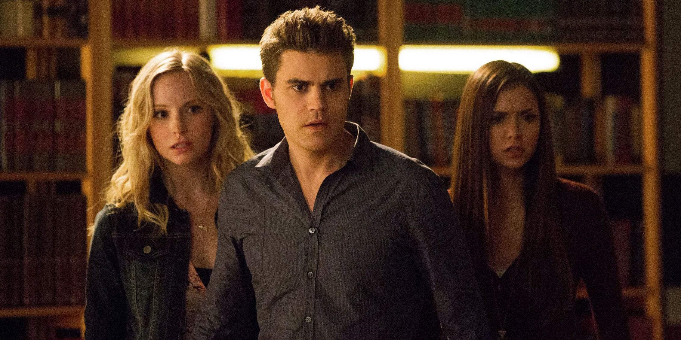 Stefan standing in front of Caroline and Elena in The Vampire Diaries.