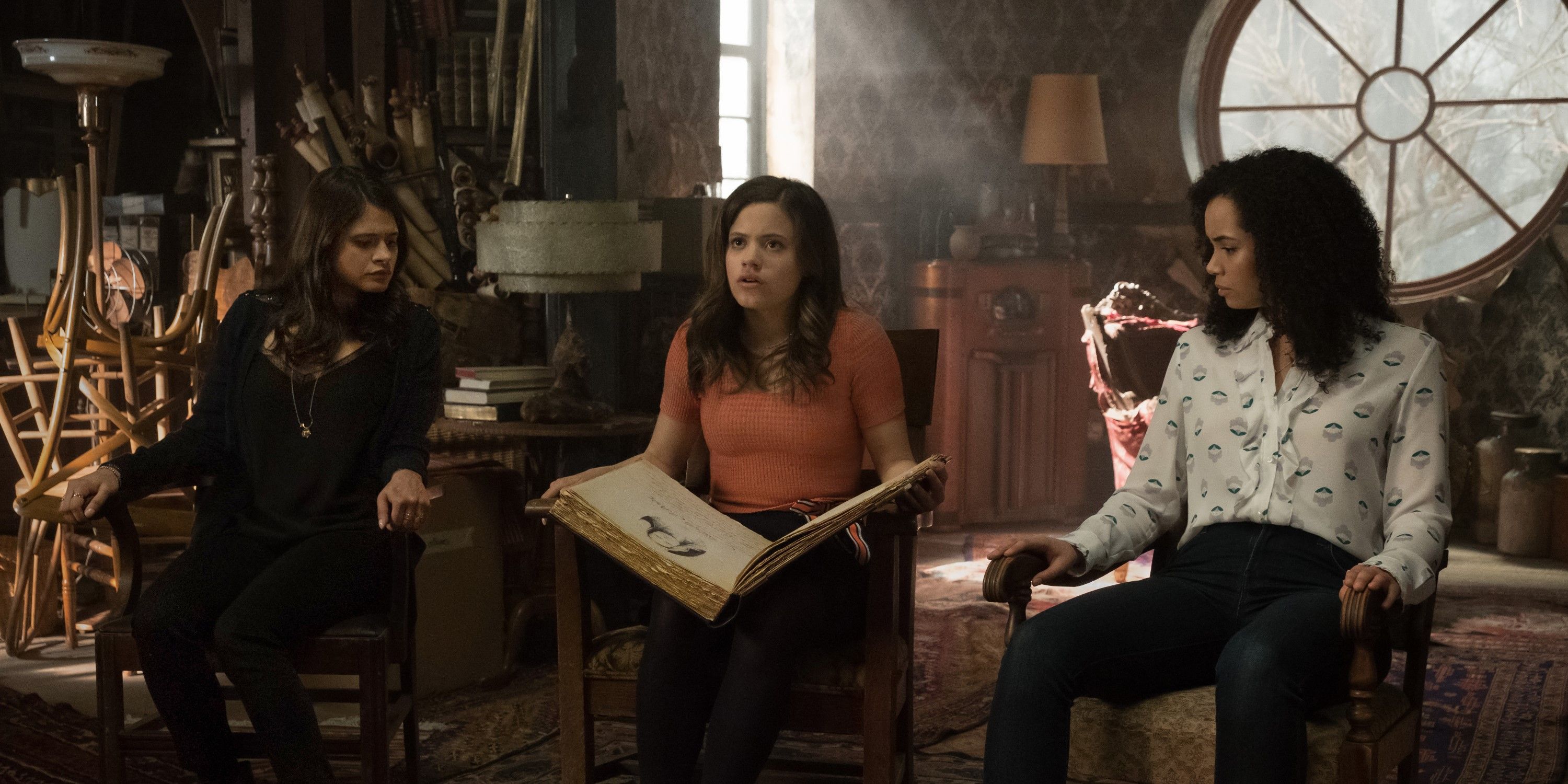 Mel, Maggie, and Macy sitting in chairs in the attic with their mother's book of shadows in the Charmed reboot