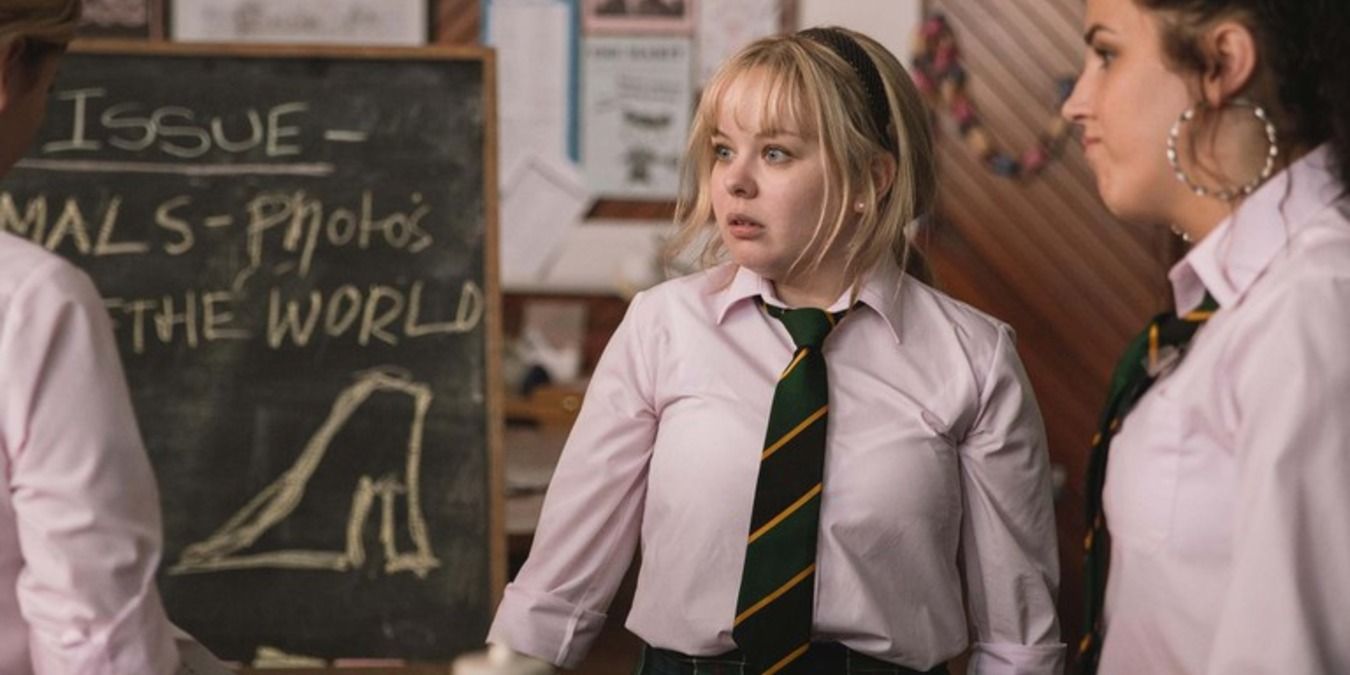 Clare and Michelle stand in front of a chalkboard in Derry Girls