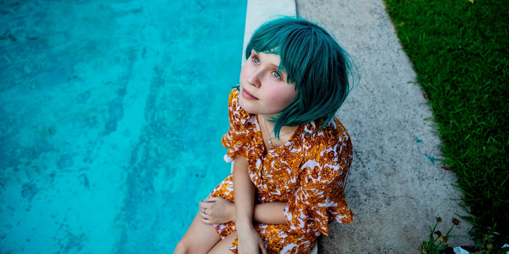 Eliza Scanlen as Milla sitting by the poolside with blue hair staring up at the sky