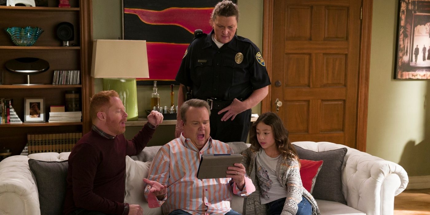 Mitch, Cam, and Lily on the couch with a police officer behind them on modern Family