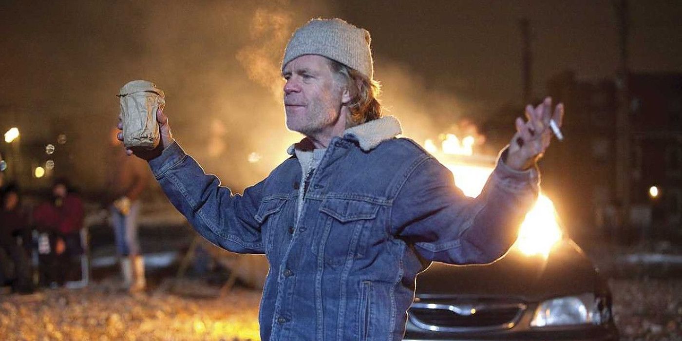 Frank Gallagher standing in front of a burning car in Shameless