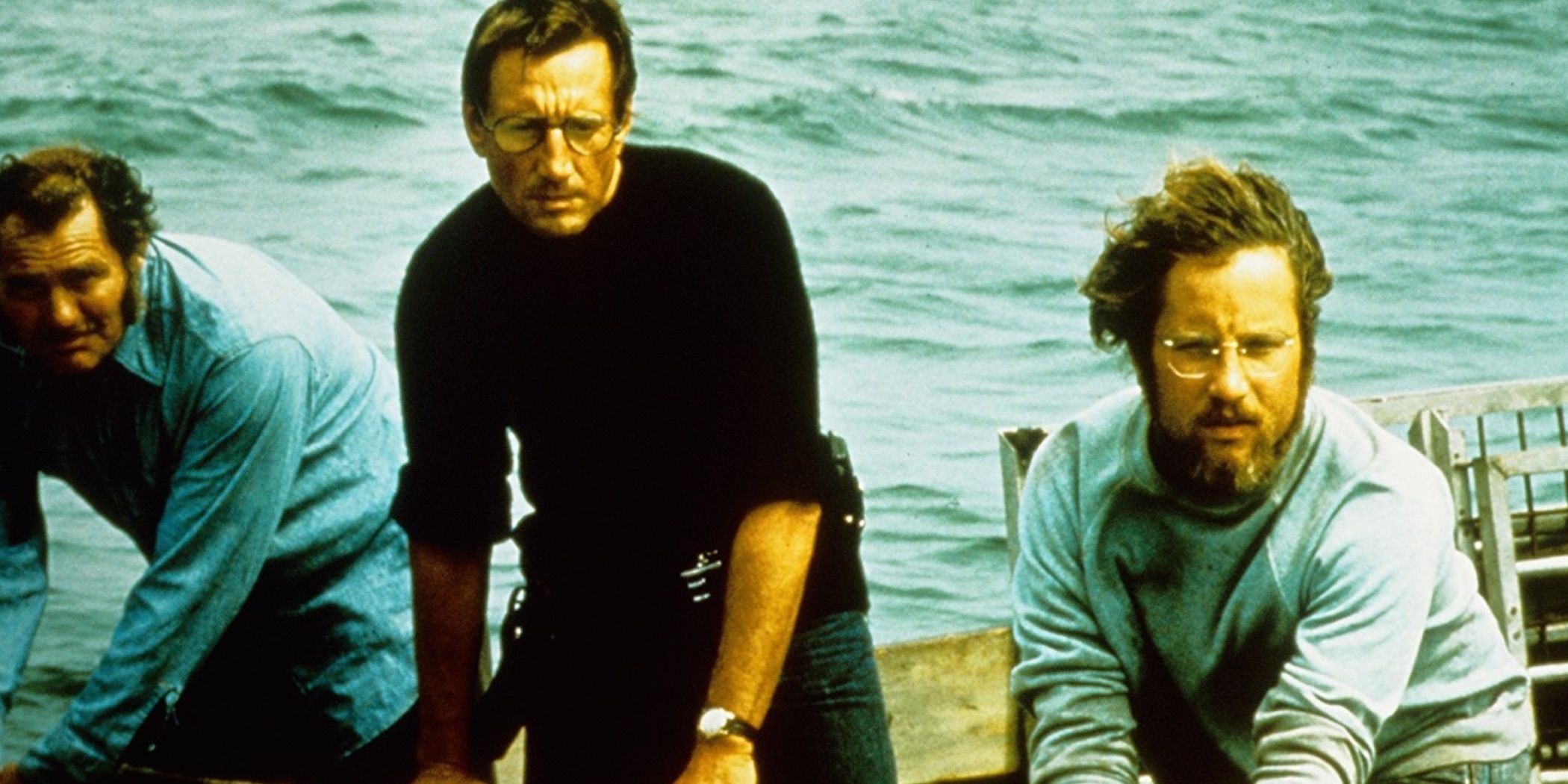 Three men look on as the sea rages behind them in Jaws.