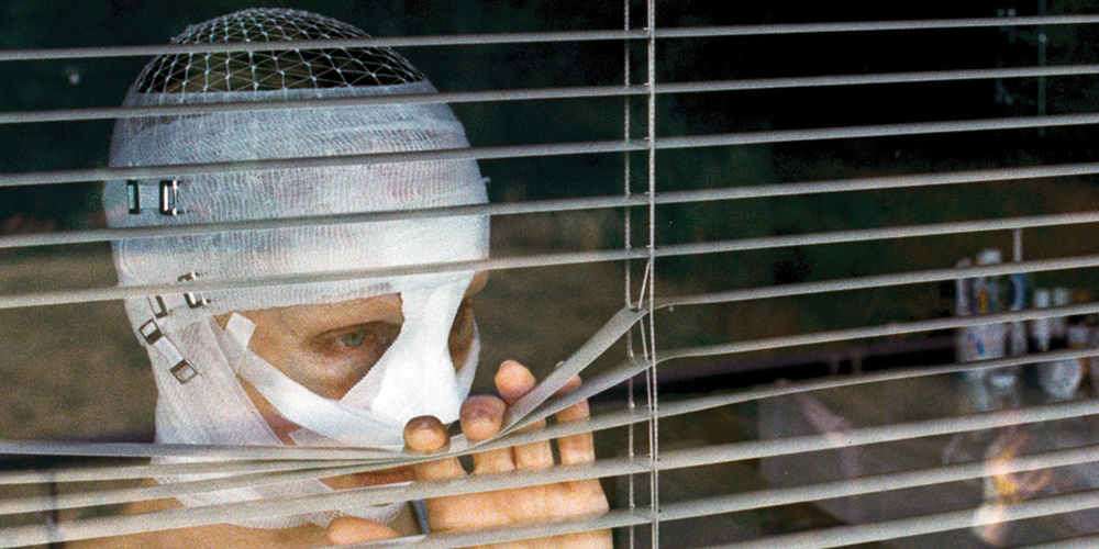 Mother's bandaged face peers out a window in Goodnight Mommy.