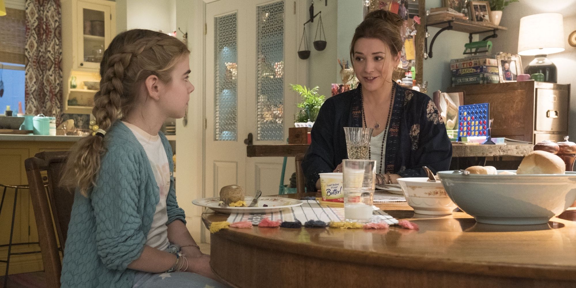 Matilda Lawler and Alyson Hannigan sitting at a dining room table in Flora and Ulysses