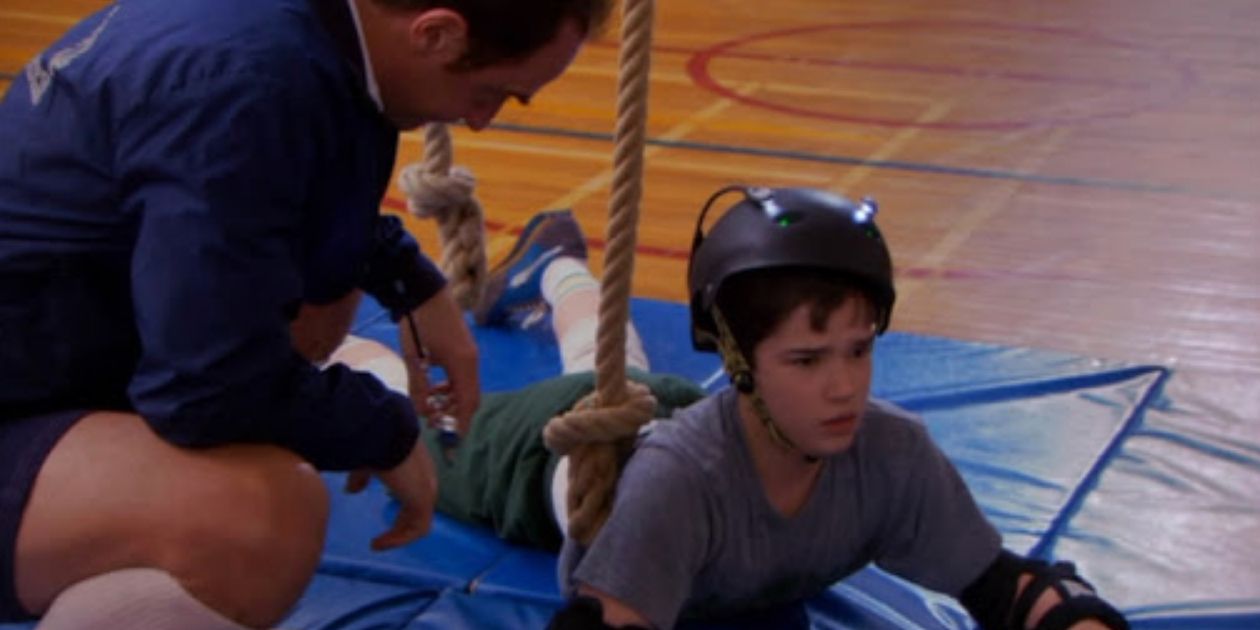 Roland falls from the climbing rope while his gym teacher looks on