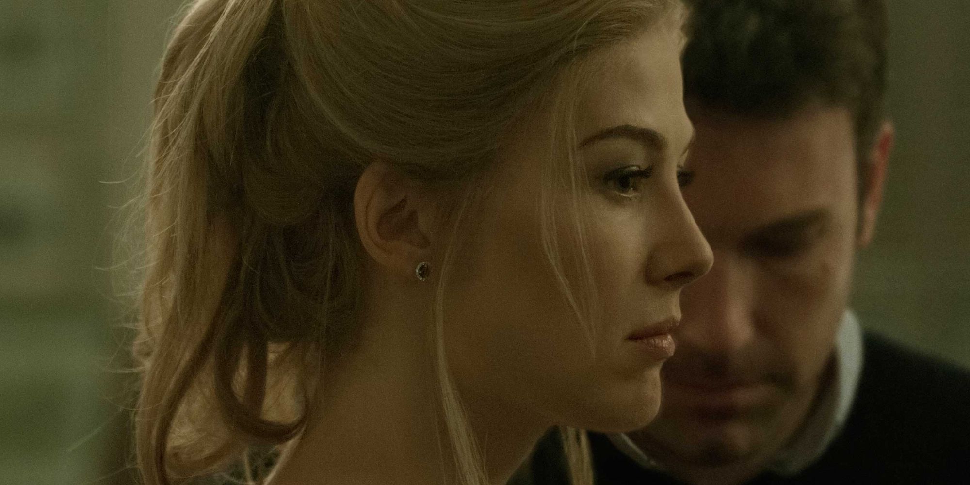 Rosamund Pike stares off with Ben Affleck in the background
