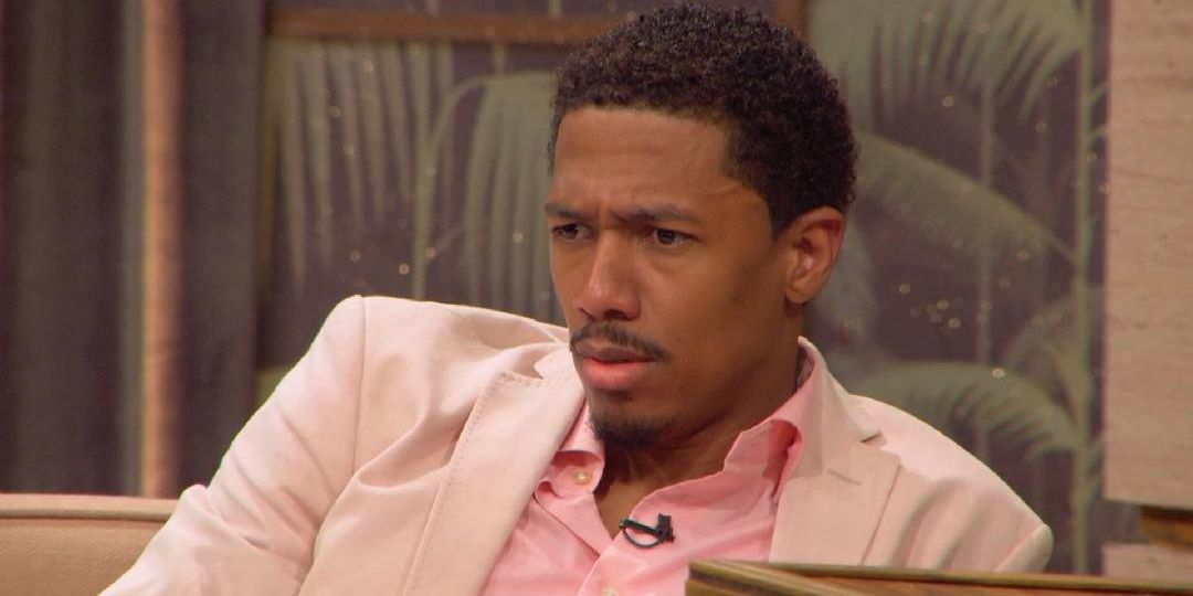 Nick Cannon wearing a pink suit, squinting his eyes.