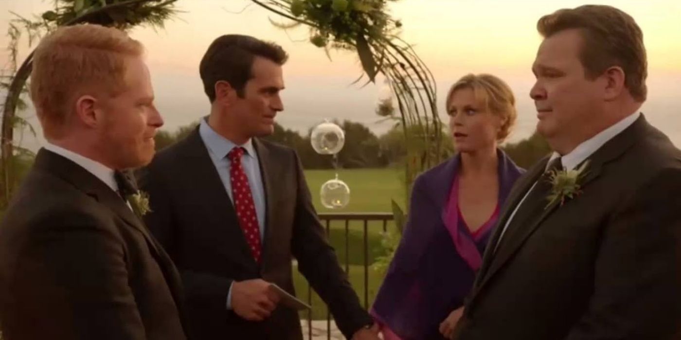 Phil and Claire standing with Mitch and Cam at their wedding on Modern Family
