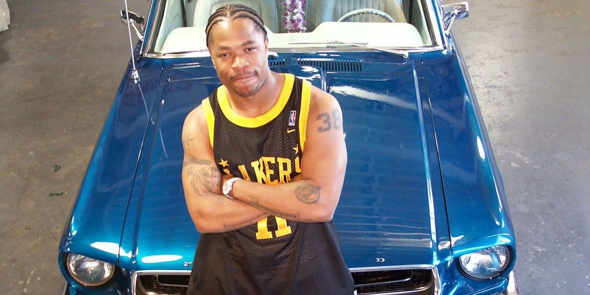 Xzibit leaning against the hood of a car with his arms crossed in Pimp My Ride
