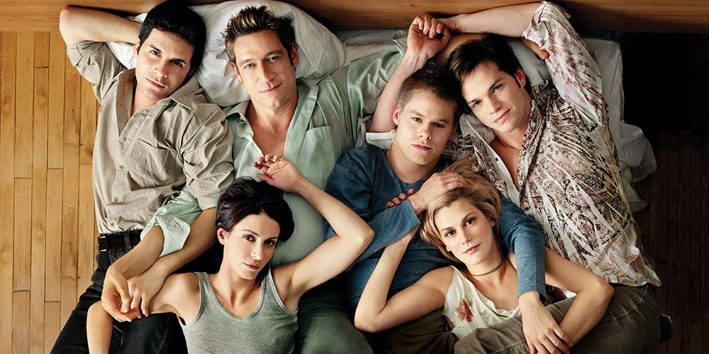 Queer As Folk cast lay on the ground and look up the camera.