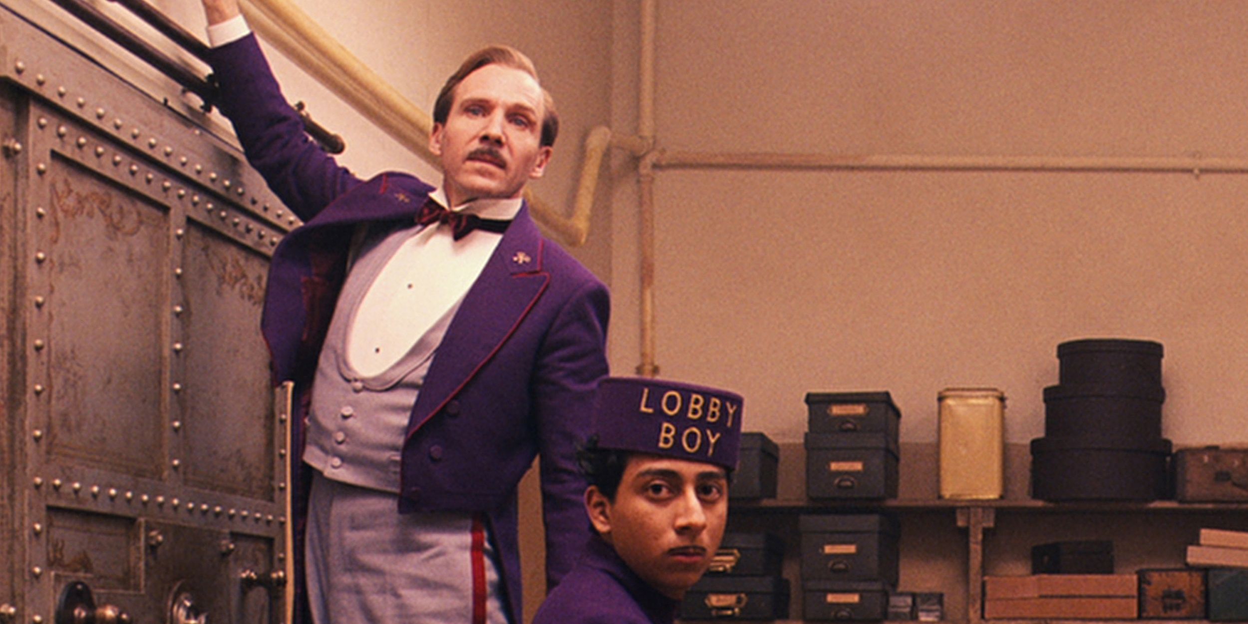 Ralph Fiennes reaches up in The Grand Budapest Hotel