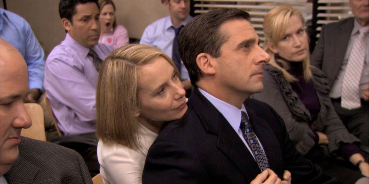 Michael sits on Holly's lap in office meeting. Everyone else looks uncomfortable.