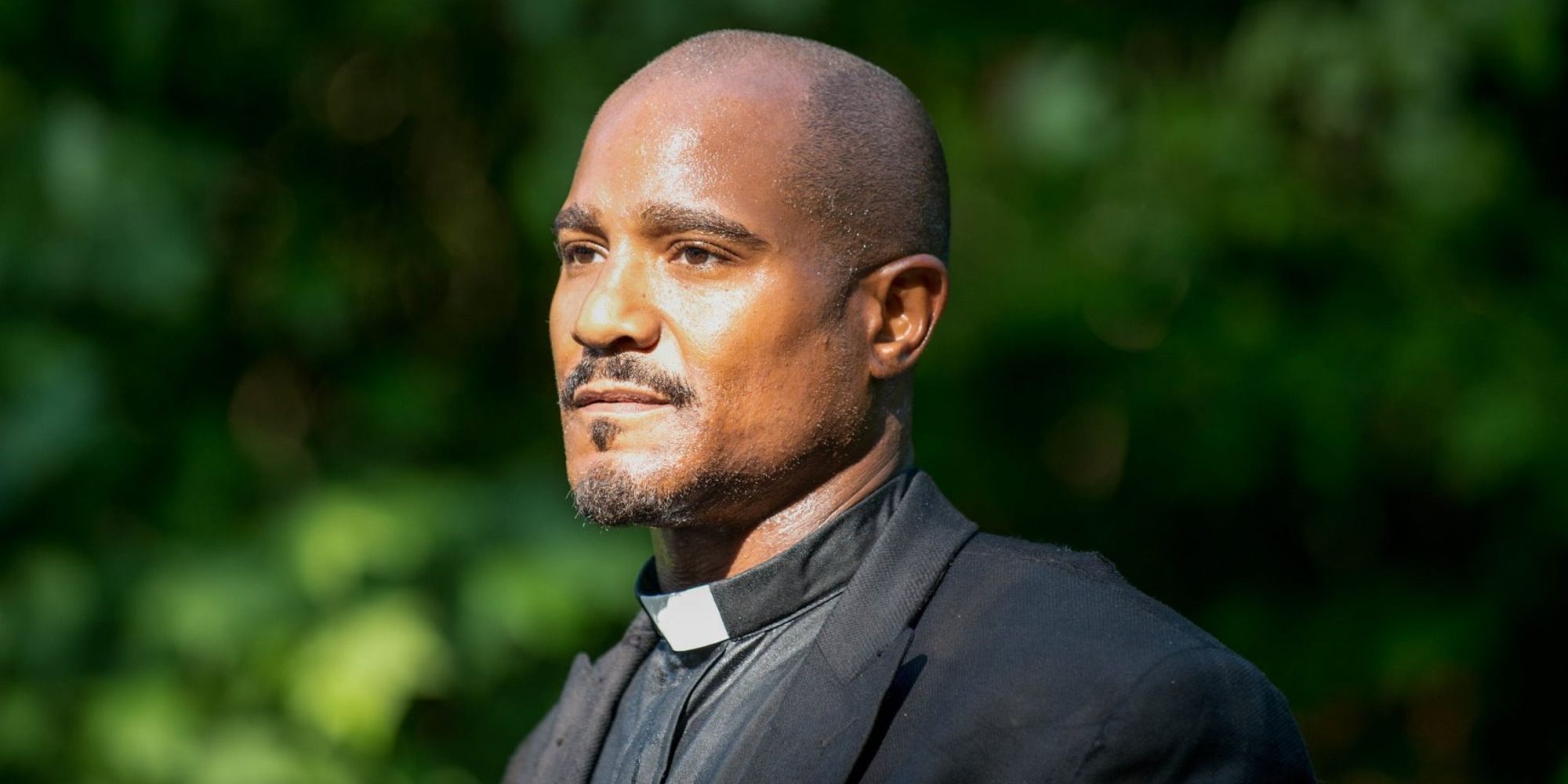 Gabriel Stokes from The Walking Dead standing in the sun, looking to the left.
