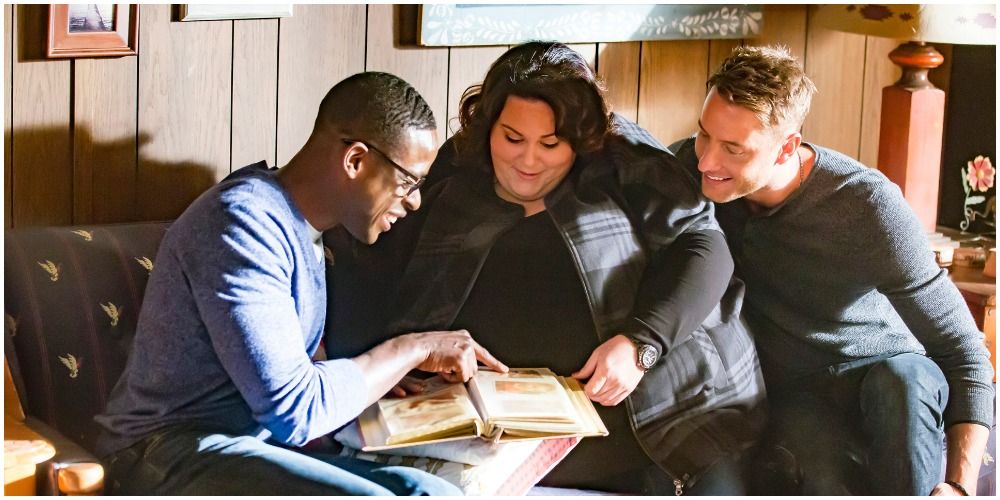 a black man, white woman and white man looking at a photo album