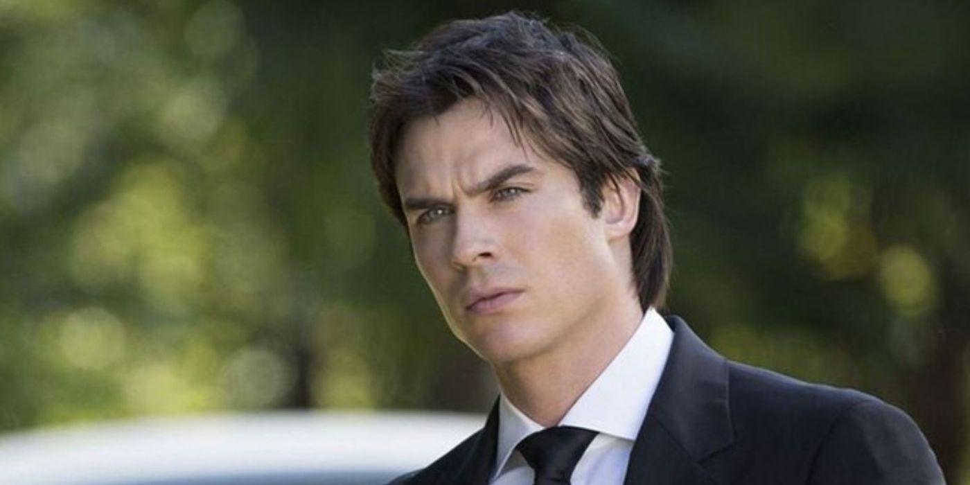 Dressed in a suit and standing outdoors, Damon Salvatore stares off in The Vampire Diaries