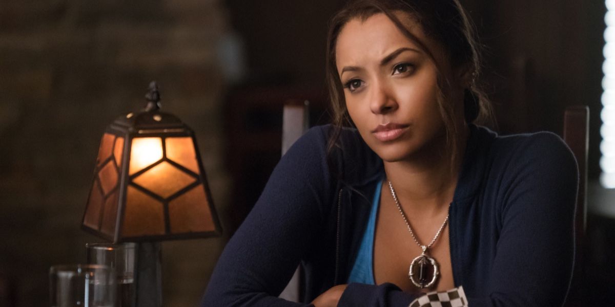 Bonnie leaning over a table, looking serious in The Vampire Diaries